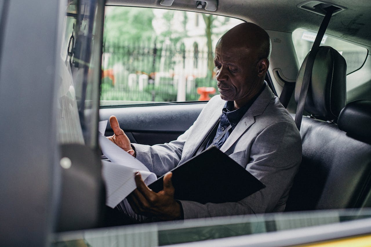 Crafting Captivating Headlines: Your awesome post title goes here African American businessman reading documents inside a car, demonstrating focus and professionalism.